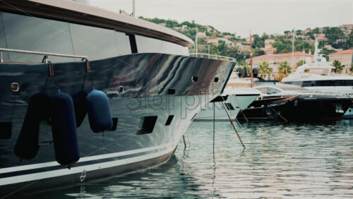 Video - Close up of a yacht's metallic hull reflecting the surrounding marina and water ripples