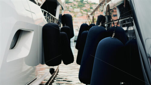 Video - Close up of blue fenders hanging between two docked yachts, gently touching as the boats move on calm water
