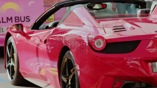 Video - Cannes, France - October 4, 2025: Rear view of a red convertible Ferrari car driving through a city street