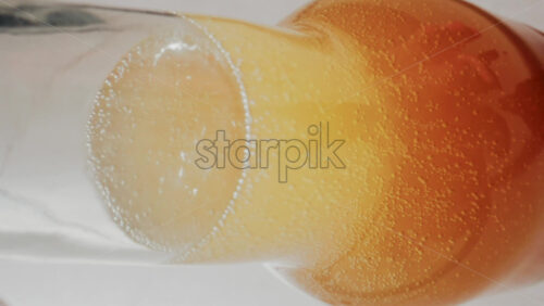 Video - Close up view of fizzy drink with golden bubbles rising inside a glass. Vertical