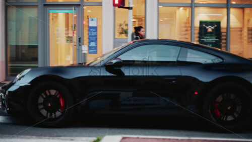 Video - Cannes, France - October 31, 2025: A glossy black Porsche 911 gleams under soft evening light, its curves perfectly defined