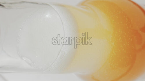 Video - Close up view of fizzy drink with golden bubbles rising inside a glass. Vertical