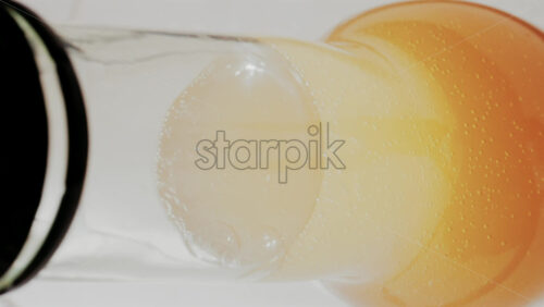 Video - Close up view of fizzy drink with golden bubbles rising inside a glass. Vertical