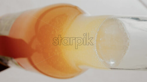 Video - Close up view of fizzy drink with golden bubbles rising inside a glass. Vertical