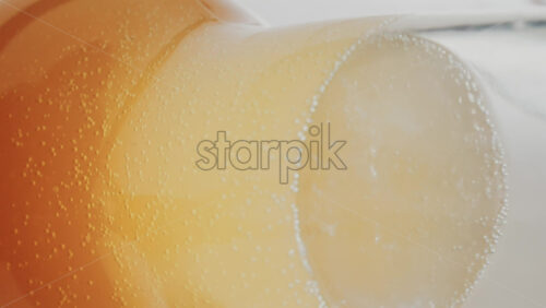 Video - Close up view of fizzy drink with golden bubbles rising inside a glass. Vertical