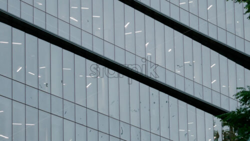 Video - Architectural shot of a modern office building with reflective glass panels and geometric lines