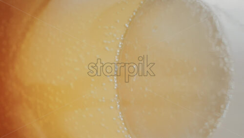 Video - Close up view of fizzy drink with golden bubbles rising inside a glass. Vertical