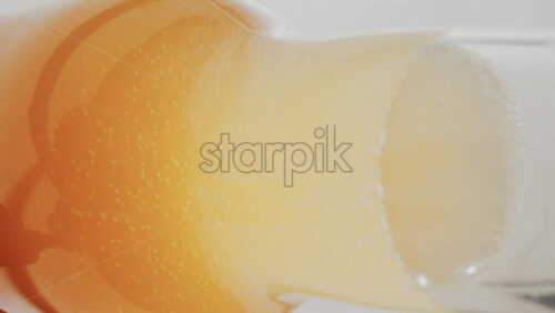 Video - Close up view of fizzy drink with golden bubbles rising inside a glass. Vertical