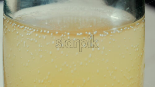Video - Close up view of fizzy drink with golden bubbles rising inside a glass