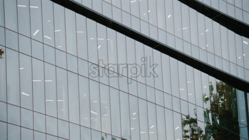 Video - Architectural shot of a modern office building with reflective glass panels and geometric lines