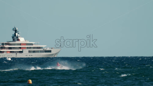 Video - Cannes, France - October 4, 2025: Black speed boat creating splashes while racing on deep blue sea near rocky coastline and luxury villas