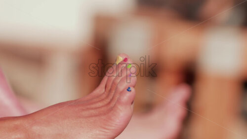 Video - Close up of a woman's foot with colorful toenail polish relaxing at the beach under sunlight