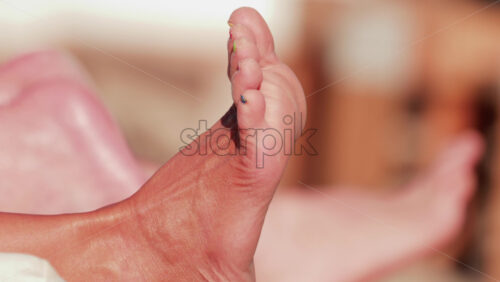 Video - Close up of a woman's foot with colorful toenail polish relaxing at the beach under sunlight