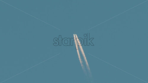 Video - Airplane flying high above leaving long contrails in a clear blue sky