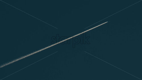 Video - Airplane flying high above leaving long contrails in a clear blue sky