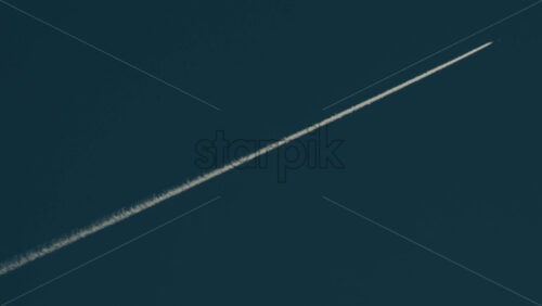 Video - Airplane flying high above leaving long contrails in a clear blue sky