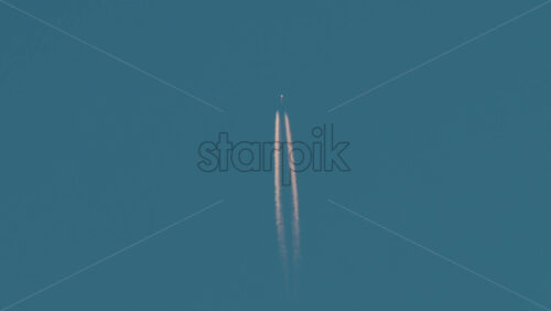 Video - Airplane flying high above leaving long contrails in a clear blue sky