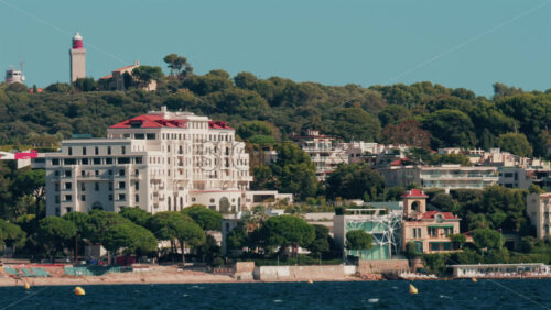 Video - Scenic view of coastal architecture and lighthouse surrounded by trees and hills in Cannes, France