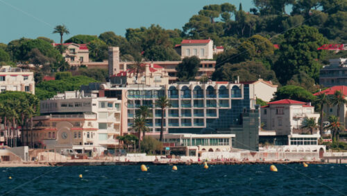 Video - Scenic view of coastal architecture and lighthouse surrounded by trees and hills in Cannes, France
