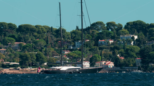 Video - Large sailing yacht anchored near the French Riviera coastline surrounded by trees and villas