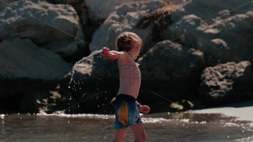 Video - Cannes, France - October 5, 2025: Young boy splashing water at the beach on a sunny day