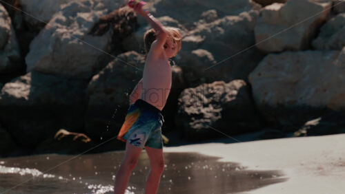 Video - Cannes, France - October 5, 2025: Young boy splashing water at the beach on a sunny day