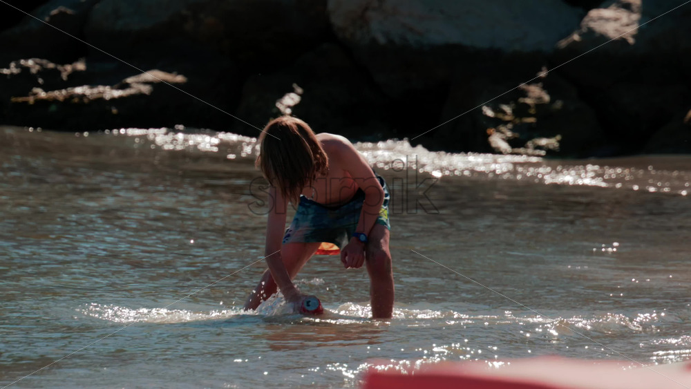 Video - Cannes, France - October 5, 2025: Young boy splashing water at the beach on a sunny day