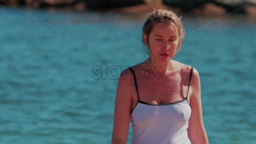 Video - Woman in a white swimsuit walking in shallow sea water on a sunny day in Cannes, France