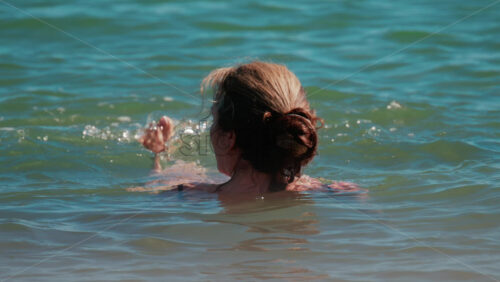 Video - Woman swimming in the calm blue sea under sunlight in Cannes, France
