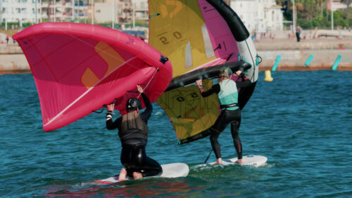 Video - Cannes, France - October 6, 2025: A man and woman on wing foil boards holding colorful sails ride side by side on the turquoise sea