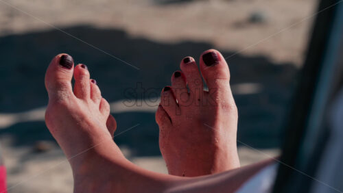Video - Close up of sandy feet resting on a sunny beach in Cannes, France
