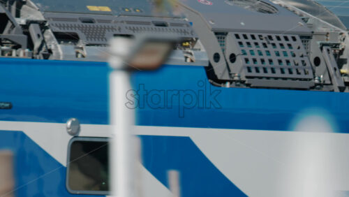 Video - Cannes, France - October 6, 2025: A modern blue regional train passes along the seaside railway, with palm trees and people in the foreground