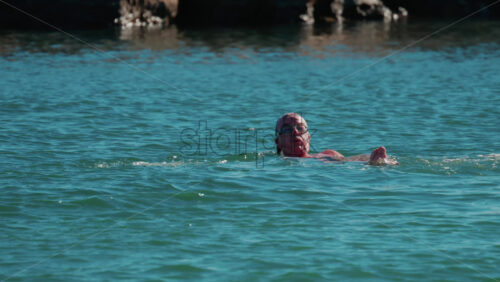 Video - Cannes, France - October 6, 2025: Man swimming on his back in the calm turquoise water off the coast