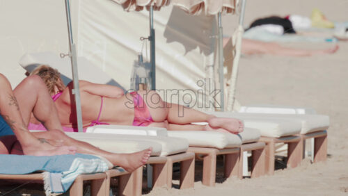 Video - People sunbathing on comfortable loungers under umbrellas on a bright summer day in Cannes, France