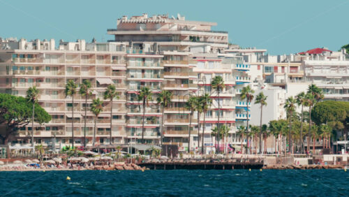 Video - Coastal view of modern apartments and tall palm trees along the waterfront in Cannes, France