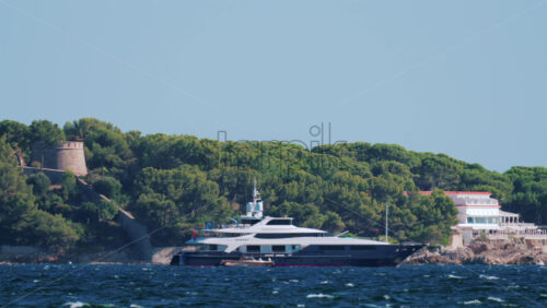 Video - A large luxury yacht sails near the forested coastline of Cannes, France