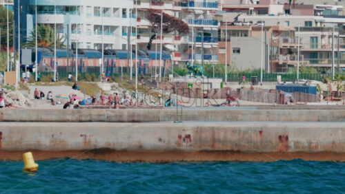 Video - Cannes, France - October 7, 2025: A train passes by a crowded beach as people relax by the sea