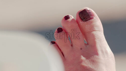 Video - Close up of a sandy foot resting on a sunny beach in Cannes, France