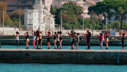 Video - Cannes, France - October 7, 2025: A group of people practicing dance or fitness on a pier by the sea on a sunny day