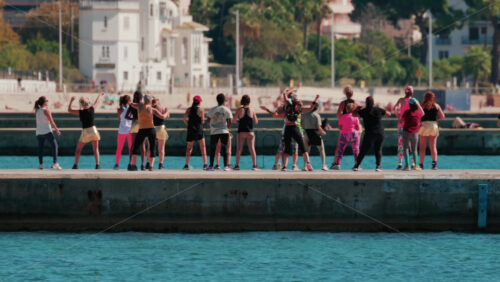 Video - Cannes, France - October 7, 2025: A group of people practicing dance or fitness on a pier by the sea on a sunny day