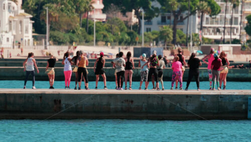 Video - Cannes, France - October 7, 2025: A group of people practicing dance or fitness on a pier by the sea on a sunny day