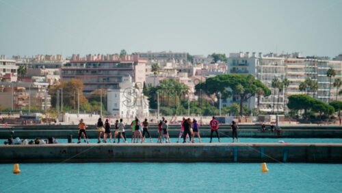 Video - Cannes, France - October 7, 2025: A group of people practicing dance or fitness on a pier by the sea on a sunny day