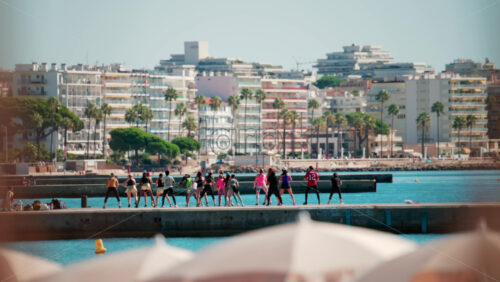 Video - Cannes, France - October 7, 2025: A group of people practicing dance or fitness on a pier by the sea on a sunny day