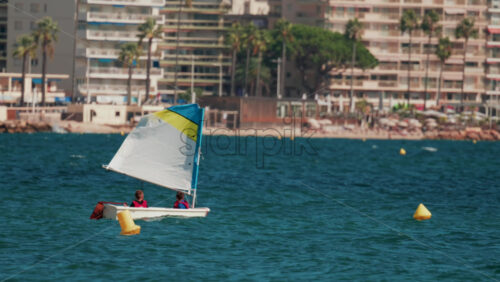 Video - Children in small sailboats learning to navigate on the blue sea near a beach resort
