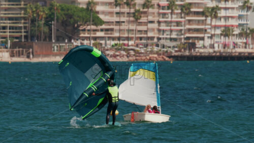 Video - Cannes, France - October 7, 2025: A man practices wing foiling, balancing on a board while holding an inflatable sail on turquoise water near the shore