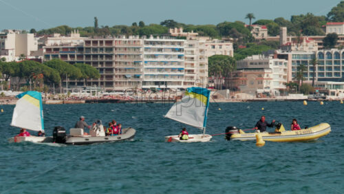 Video - Cannes, France - October 7, 2025: Children learning to sail in small boats accompanied by instructors in motorboats