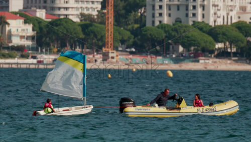 Video - Cannes, France - October 7, 2025: Children learning to sail in small boats accompanied by instructors in motorboats