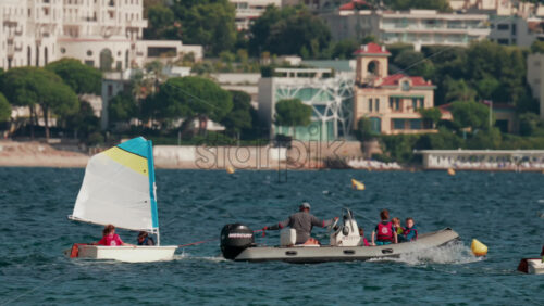 Video - Cannes, France - October 7, 2025: Children learning to sail in small boats accompanied by instructors in motorboats