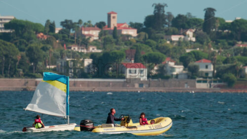 Video - Cannes, France - October 7, 2025: Children learning to sail in small boats accompanied by instructors in motorboats