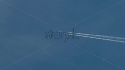 Video - Airplane flying high above leaving long contrails in a clear blue sky